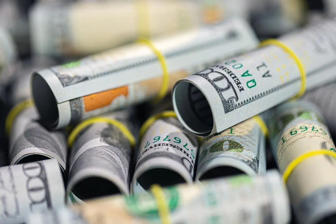 Detailní záběr zkroucených stodolarových bankovek, pozadí s finanční tematikou.